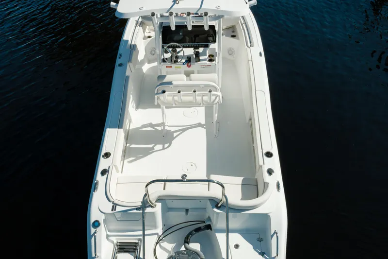 Slide: The Image of 2004 Sea Hunt Ultra 234 boat interior, white deck, and seating on calm water. - 3