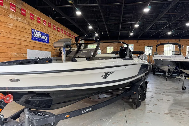 The Image of 2026 Lund 202 Pro-V GL boat displayed indoors on a trailer. - 0