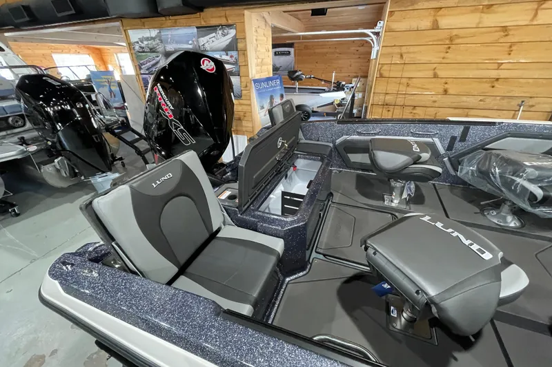 Slide: The Image of 2026 Lund 202 Pro-V GL boat interior with seating and motor in showroom. - 14
