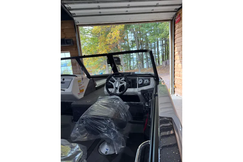 Slide: The Image of 2026 Lund 202 Pro-V GL boat interior in garage with forest view. - 3