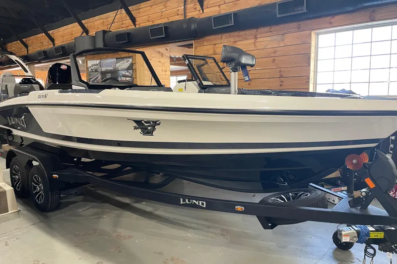 Slide: The Image of 2026 Lund 202 Pro-V GL boat displayed indoors on a trailer. - 9