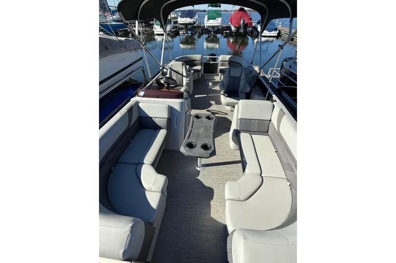 Slide: The Image of 2023 Bennington 22SX Stern Radius pontoon boat interior with seating and table, docked at marina. - 9