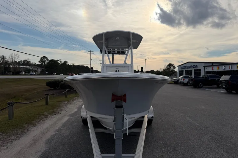 Slide: The Image of 2024 Sea Hunt Ultra 229 boat on trailer, parked near showroom under cloudy sky. - 7