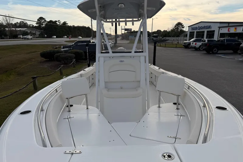 Slide: The Image of 2024 Sea Hunt Ultra 229 boat, white interior, parked outdoors near a showroom. - 9