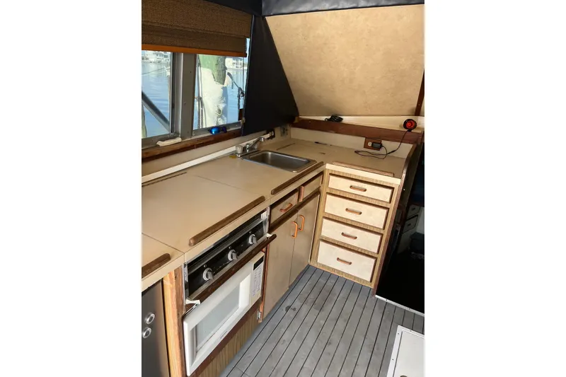 Slide: The Image of 1981 Bertram 35 Sportfish boat kitchen with stove, sink, and storage drawers. - 25