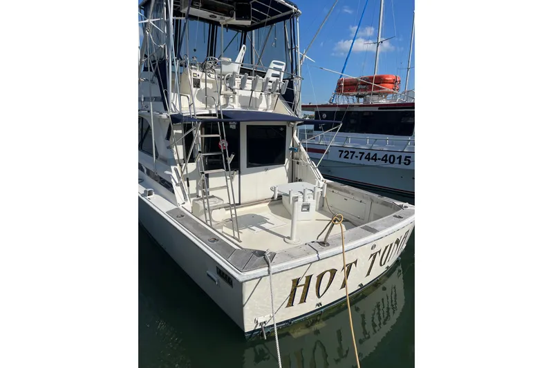 Slide: The Image of 1981 Bertram 35 Sportfish boat docked, featuring a spacious deck and fishing equipment. - 6