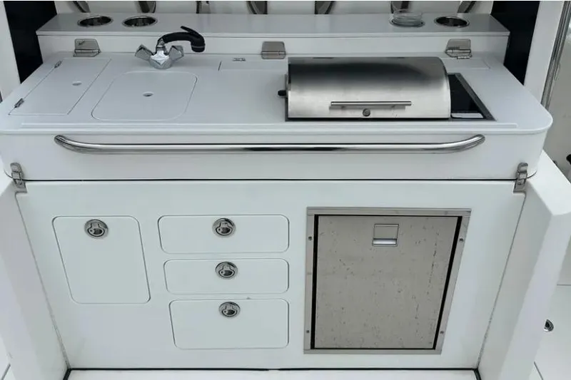Slide: The Image of 2020 Edgewater 370CC boat kitchen area with sink, grill, and storage compartments. - 10