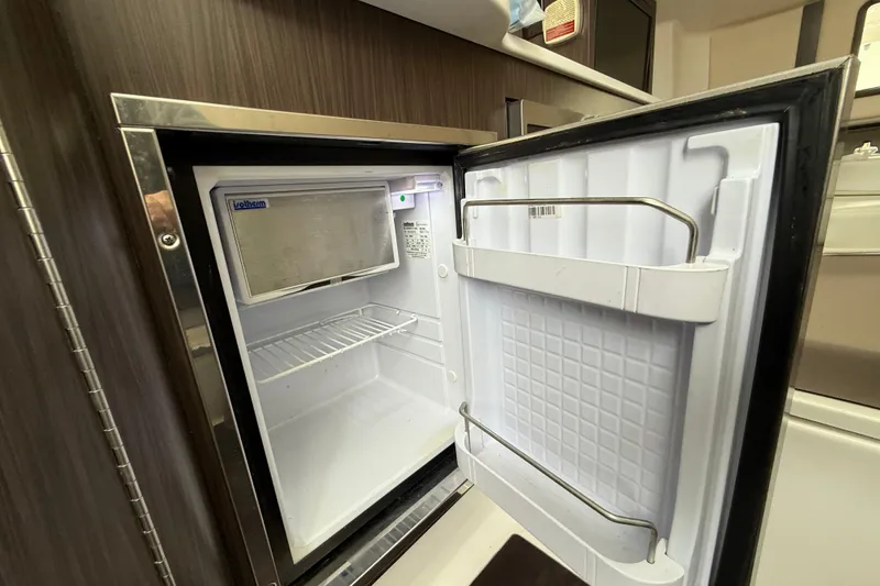 Slide: The Image of Open refrigerator inside 2020 Edgewater 370CC boat, showcasing interior storage space. - 19