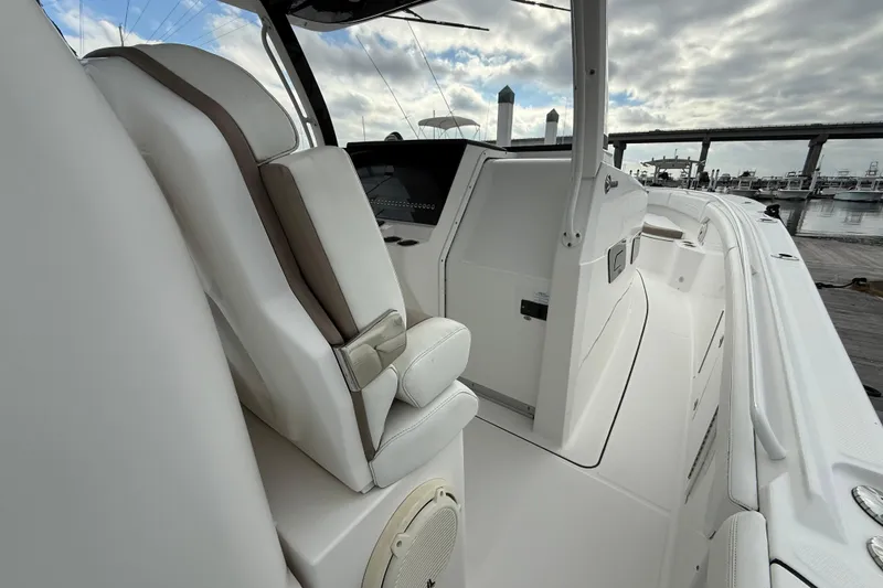 Slide: The Image of 2020 Edgewater 370CC boat interior with white seating and helm, docked at marina. - 26