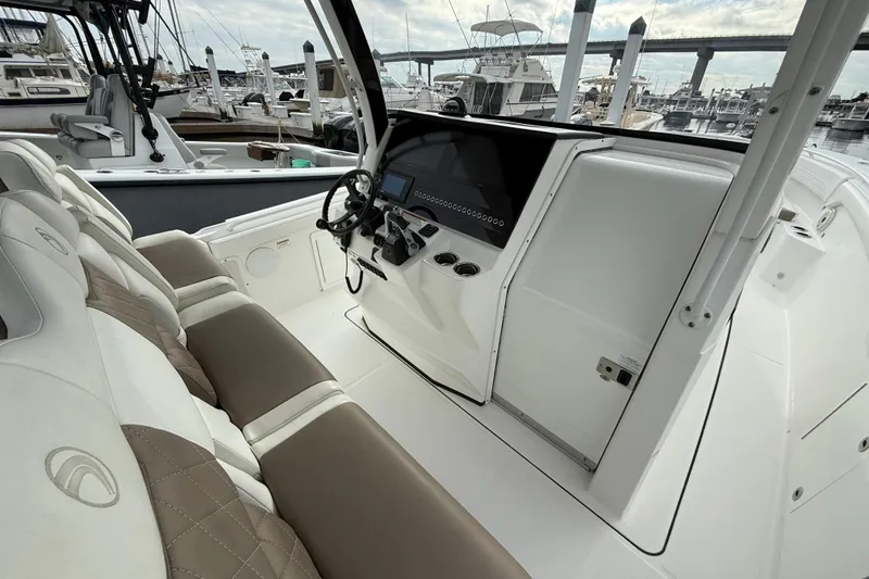 Slide: The Image of 2020 Edgewater 370CC boat interior with helm, steering wheel, and seating at marina. - 5