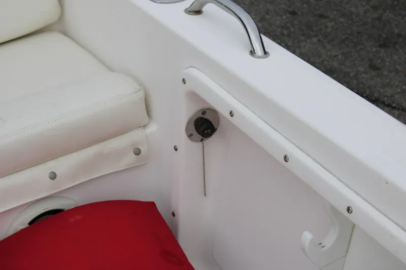 Slide: The Image of Interior of a 2005 Edgewater 185DC boat, featuring white seating and a red cushion. - 20