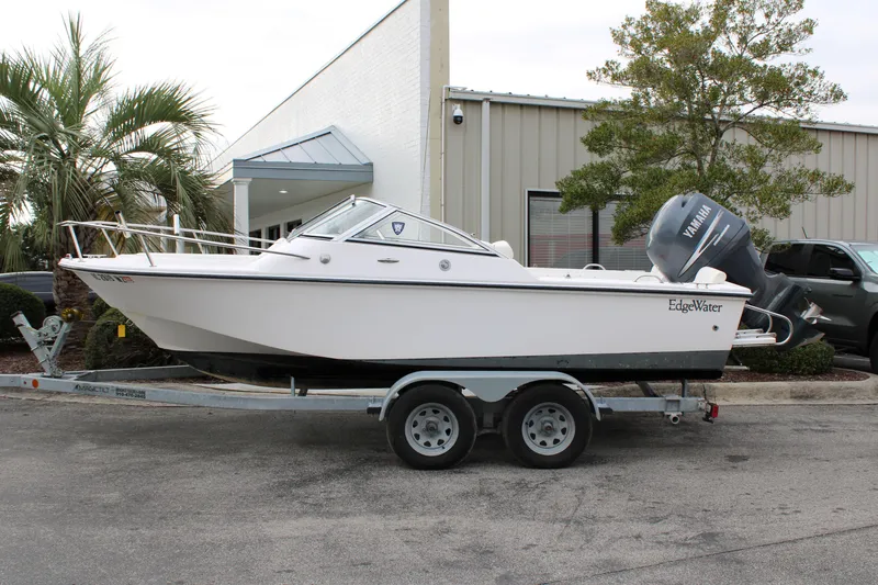 Slide: The Image of 2005 Edgewater 185DC boat on trailer, parked outside a building with palm trees. - 4
