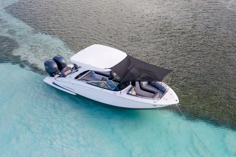 Slide: The Image of Manufacturer Provided Image: 2026 Regal LX9 boat cruising in clear turquoise waters, featuring a sleek design and sunshade. - 2