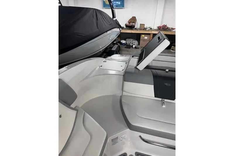 Slide: The Image of 2025 Chaparral 23 SSi boat interior with open storage compartment in a workshop setting. - 20