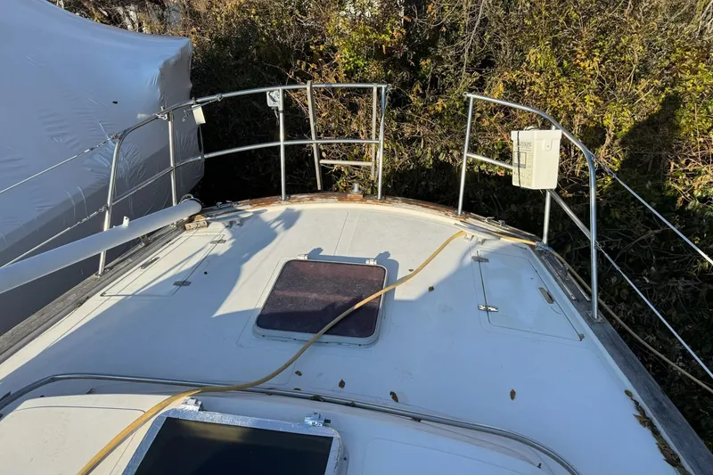 Slide: The Image of 1987 Irwin 38 Mk II sailboat deck with railing and hatch, surrounded by foliage. - 11
