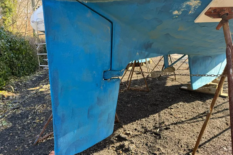 Slide: The Image of 1987 Irwin 38 Mk II sailboat hull and rudder on stands, blue paint. - 14