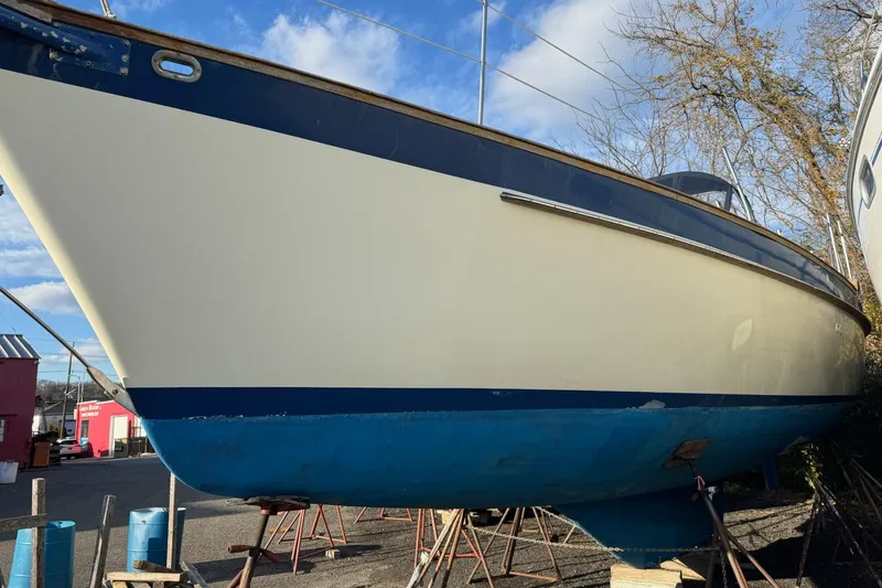 Slide: The Image of 1987 Irwin 38 Mk II sailboat on stands, blue and white hull, outdoor setting. - 2