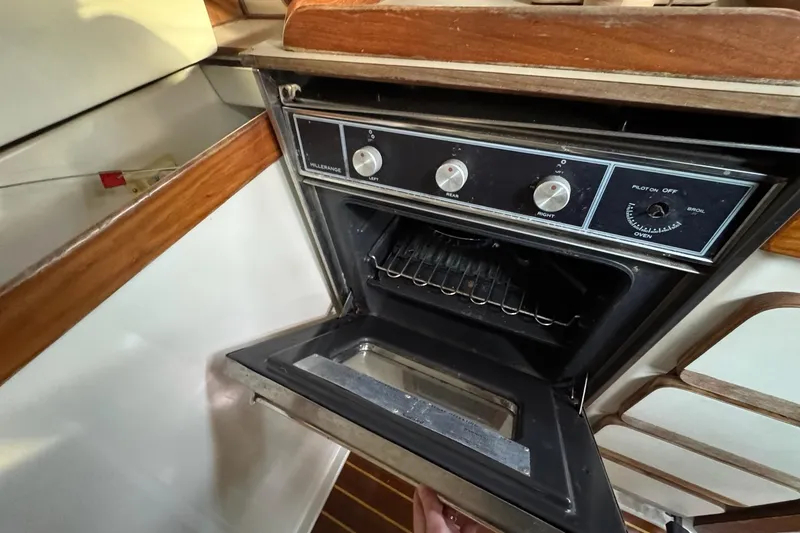 Slide: The Image of 1987 Irwin 38 Mk II yacht kitchen with an open oven, showcasing wooden cabinetry. - 25