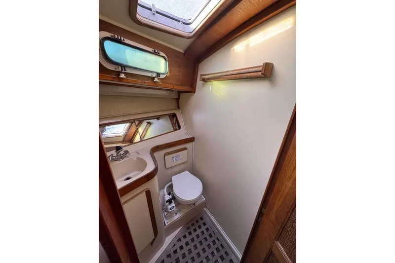 Slide: The Image of 1987 Irwin 38 Mk II yacht bathroom with sink, toilet, and porthole window. - 39