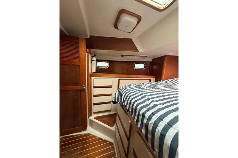 Slide: The Image of 1987 Irwin 38 Mk II yacht cabin with striped bedding and wooden interior. - 43