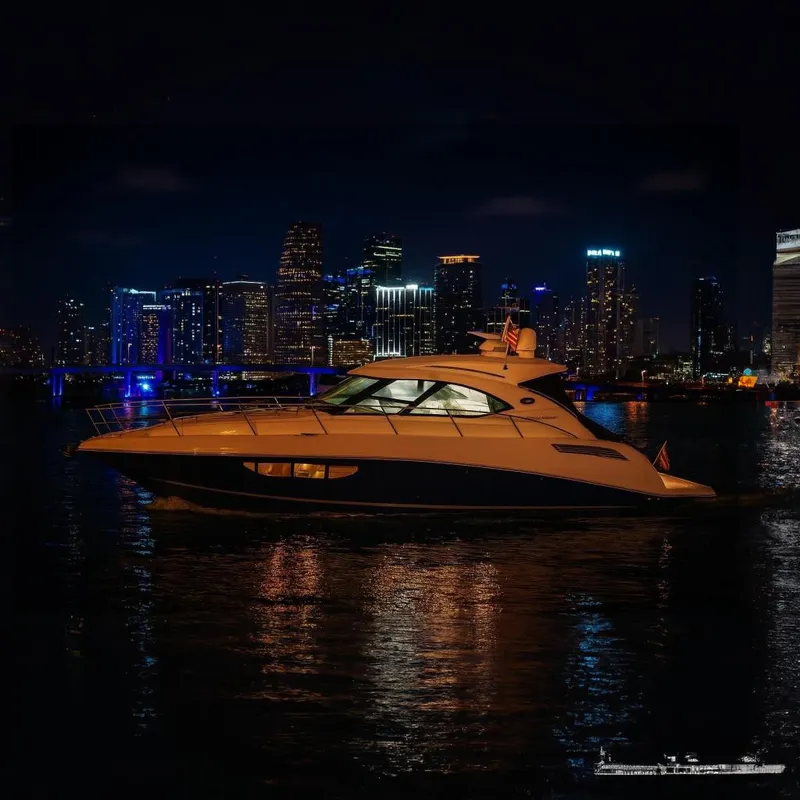Slide: The Image of 2014 Sea Ray 470 Sundancer yacht cruising at night with city skyline backdrop. - 3