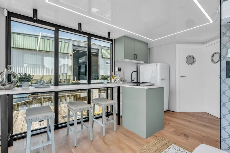 Slide: The Image of Modern Waterlodge 11 interior with sleek kitchen, bar stools, and large windows, 2025 model. - 12