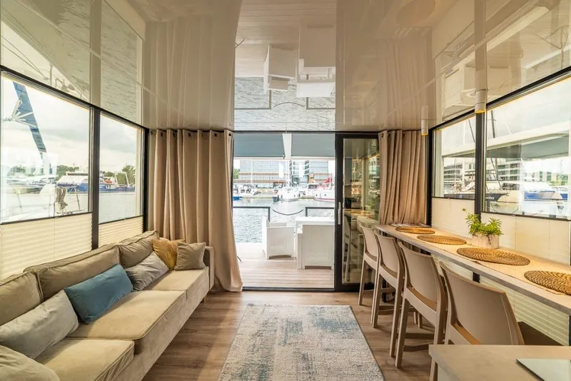 Slide: The Image of Modern Waterlodge 11 interior with cozy seating, dining area, and marina view, 2026 model. - 34