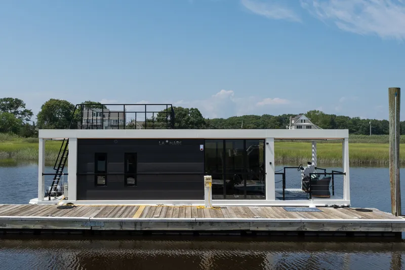 Slide: The Image of Modern Waterlodge 11 houseboat docked on a serene river, showcasing sleek design and rooftop deck. - 7