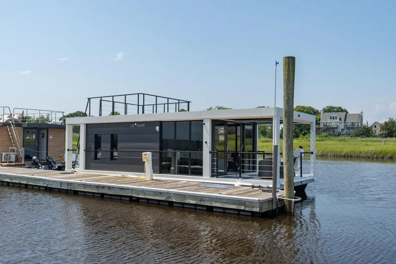 Slide: The Image of Modern Waterlodge 11 houseboat docked on a serene river, showcasing sleek design and spacious deck. - 8