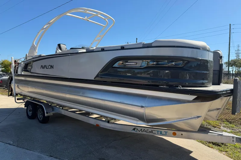 The Image of 2026 Avalon Excalibur 27' pontoon boat on trailer, sleek design, outdoor setting. - 1