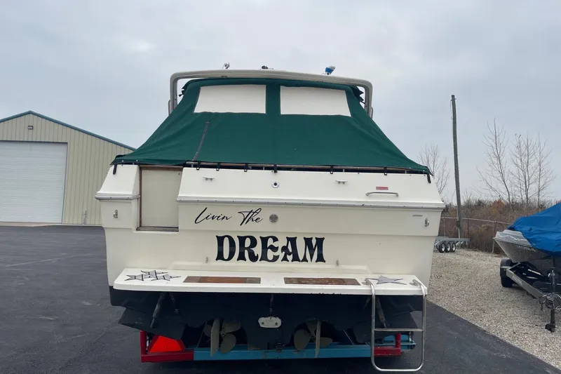 Slide: The Image of 1988 Sea Ray 300 Weekender boat on trailer, green canopy, parked near storage facility. - 3