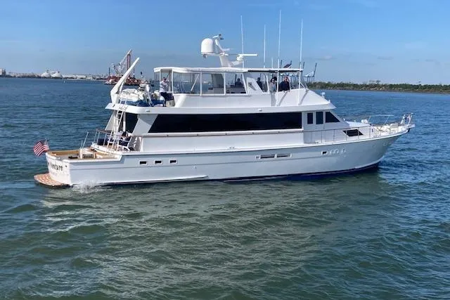 The Image of 1989 Hatteras 70 Cockpit Motor Yacht cruising on calm waters under a clear blue sky. - 0