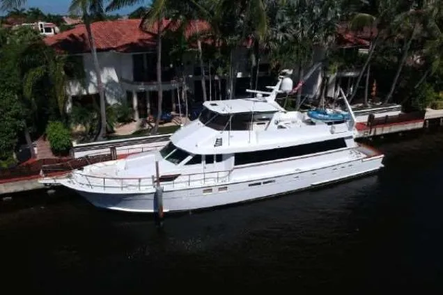 Slide: The Image of 1989 Hatteras 70 Cockpit Motor Yacht docked by waterfront homes. - 1