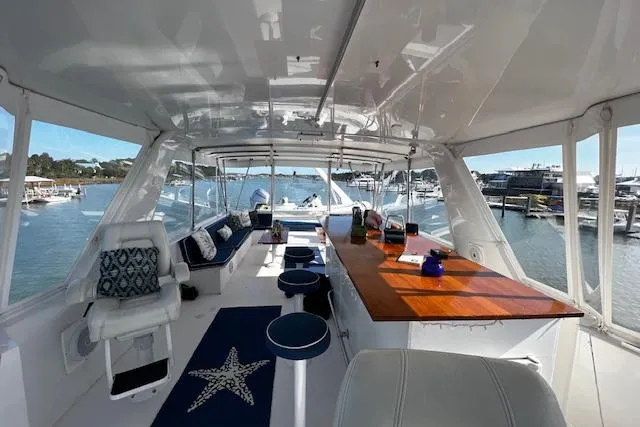 Slide: The Image of 1989 Hatteras 70 Cockpit Motor Yacht interior with seating, bar, and scenic marina view. - 14