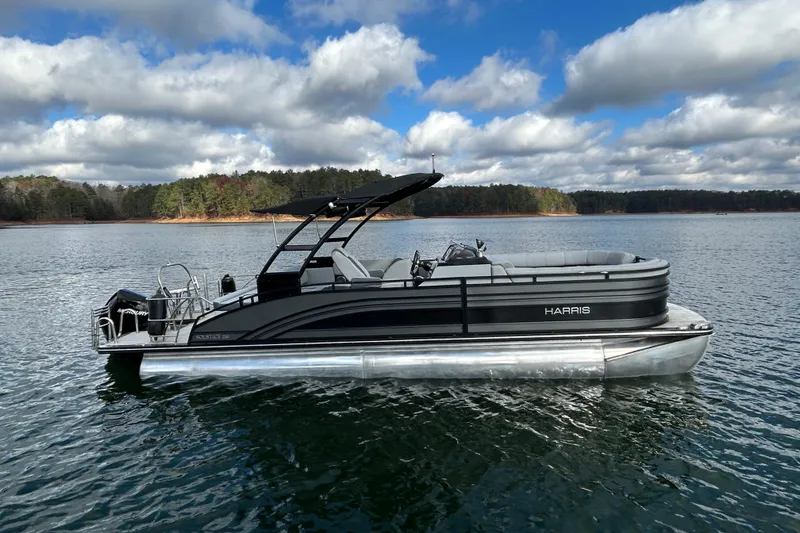 Slide: The Image of 2021 Harris Solstice 250 pontoon boat on a serene lake under a cloudy sky. - 10