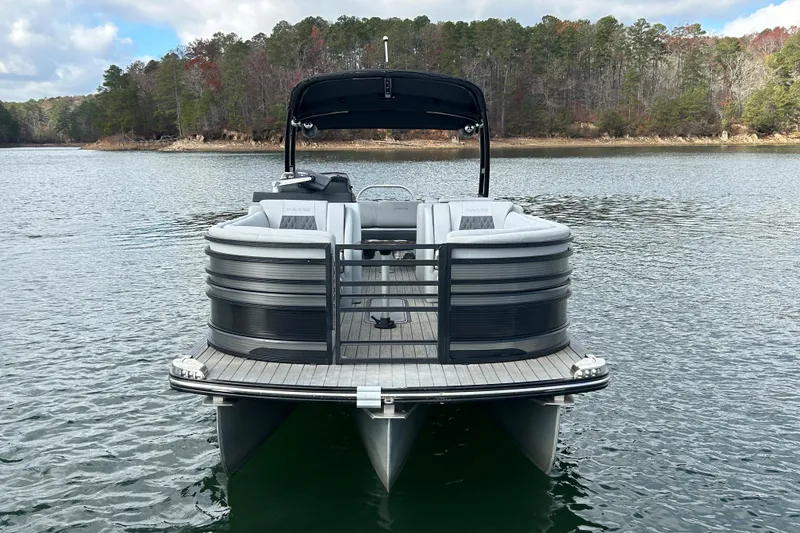 Slide: The Image of 2021 Harris Solstice 250 pontoon boat on a serene lake with forested shoreline. - 12