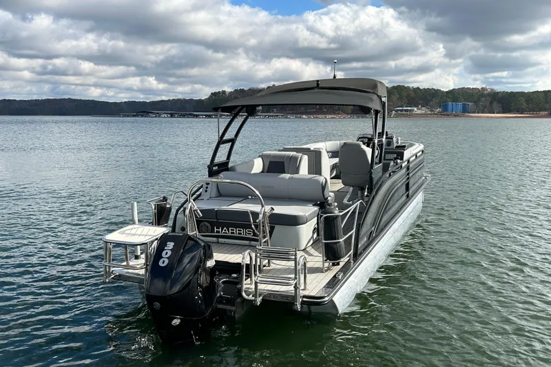 Slide: The Image of 2021 Harris Solstice 250 pontoon boat on a calm lake under cloudy skies. - 6