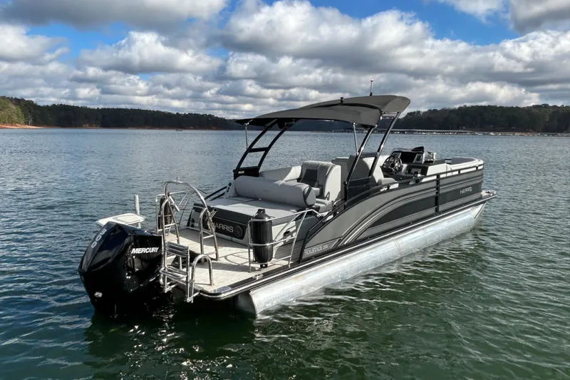 Slide: The Image of 2021 Harris Solstice 250 pontoon boat on a serene lake under cloudy skies. - 7