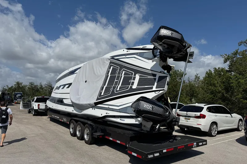 Slide: The Image of 2024 MTI 440X powerboat on trailer, parked in a lot under a clear blue sky. - 7