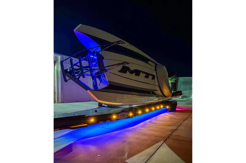 Slide: The Image of 2024 MTI 440X boat on trailer with vibrant blue and yellow lights at night. - 9