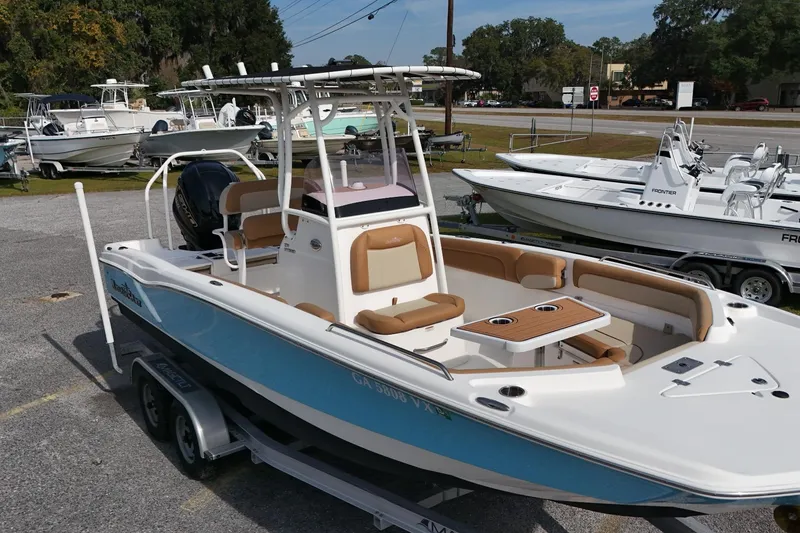 Slide: The Image of 2023 NauticStar 231 Hybrid boat with blue hull, on trailer, in outdoor showroom. - 11