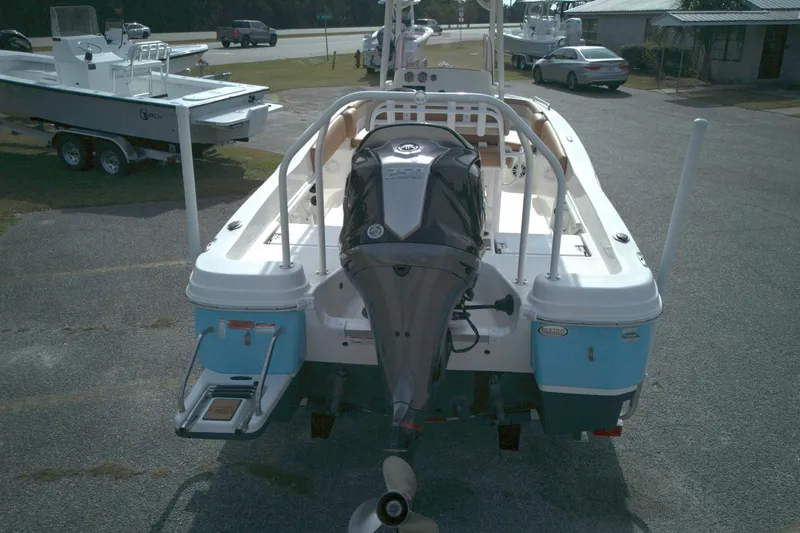 Slide: The Image of 2023 NauticStar 231 Hybrid boat, rear view with outboard motor, parked on pavement. - 13