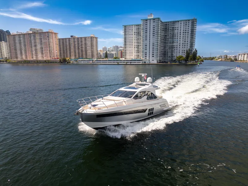 Slide: The Image of 2016 Azimut 55S yacht cruising in urban waterfront setting, high-rise buildings in background. - 3