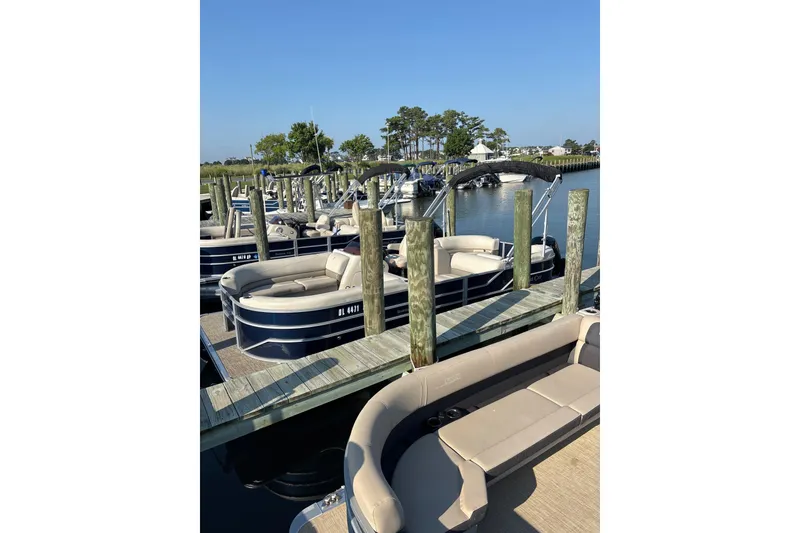 Slide: The Image of 2023 Cypress Cay Seabreeze 232 pontoon boats docked at a marina under clear blue skies. - 3