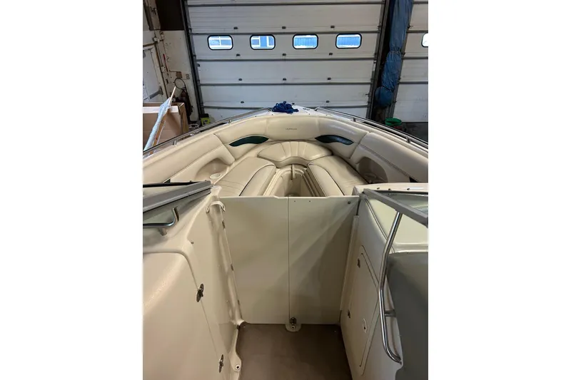 Slide: The Image of 2002 Crownline 230 BR boat interior with beige seating in a garage setting. - 18