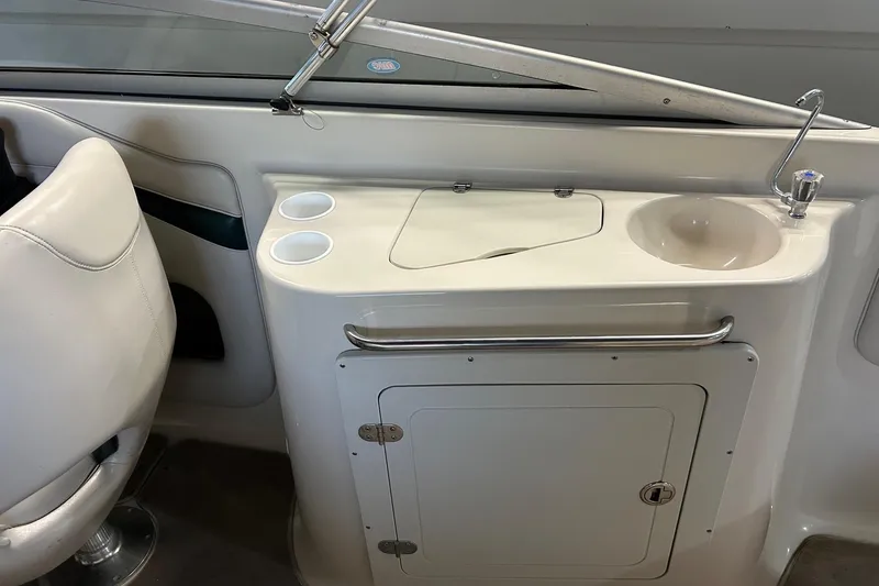 Slide: The Image of 2002 Crownline 230 BR boat interior with sink, cup holders, and storage compartment. - 30