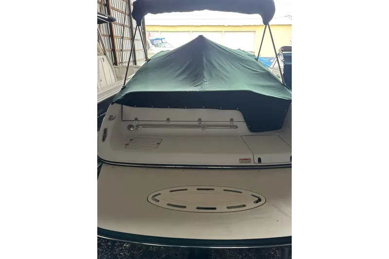 Slide: The Image of 2002 Crownline 230 BR boat with green cover in storage. - 5