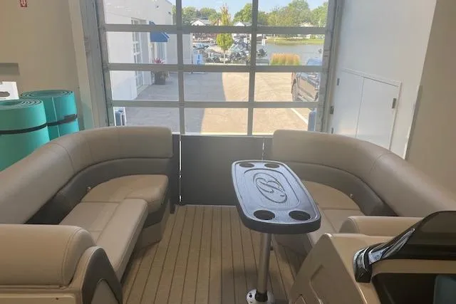 Slide: The Image of 2026 Bentley Pontoons Elite 223 Swingback interior with seating and table, docked indoors. - 10