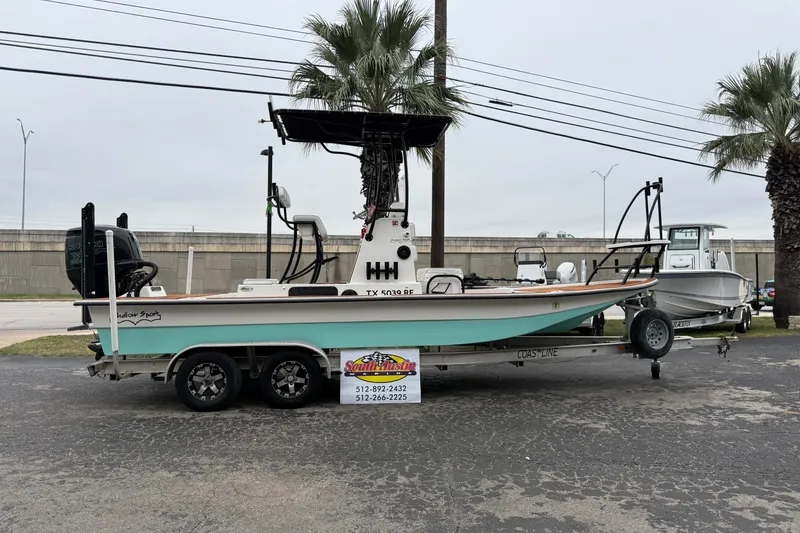 Slide: The Image of 2017 Shallow Sport 24 Sport boat on trailer, parked near palm trees. - 36