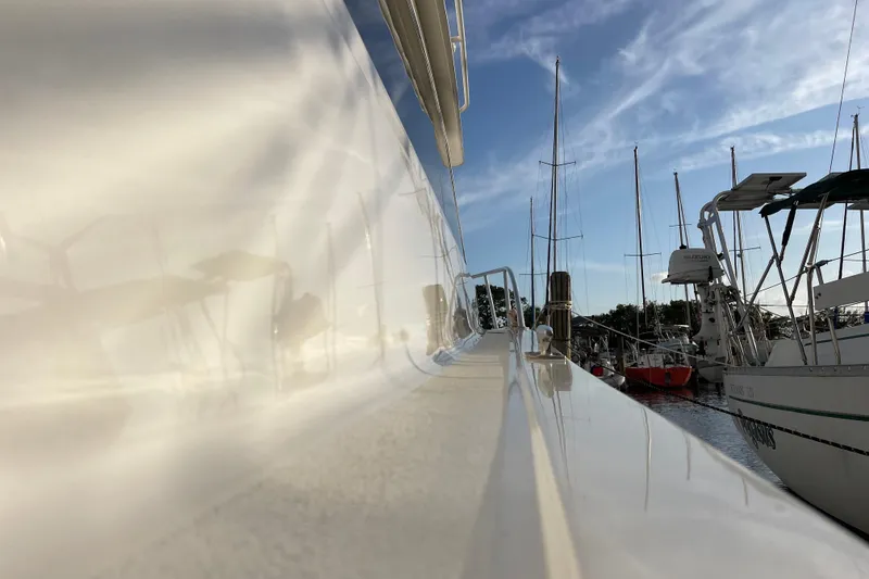 Slide: The Image of 2003 Egg Harbor 37 Sport Fisher yacht docked, reflecting sunlight, with sailboats in the background. - 34